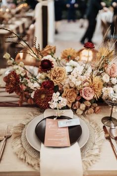 a table setting with flowers, candles and place cards on it for an elegant wedding