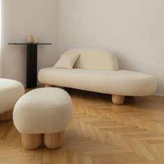 a white couch and ottoman sitting on top of a hard wood floor next to a table