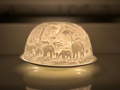 a glass bowl with elephants on it sitting on a table next to a candle holder