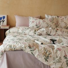 an unmade bed with white sheets and floral print on it, along with two nightstands