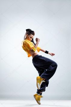 a woman in yellow shirt and black pants doing a dance move