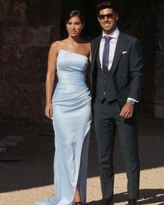 a man and woman in formal wear standing next to each other on a sunny day