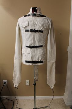 a white jacket is on a stand in front of a wall and a light switch