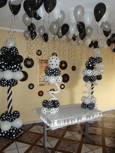 black and white balloons are hanging from the ceiling above a table with a cake on it