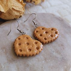 a pair of heart shaped cookies earrings on top of a rock