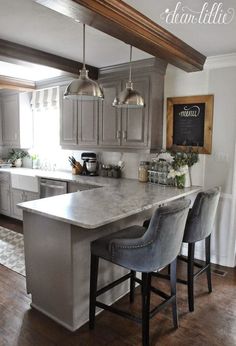 a kitchen with two bar stools next to an island in the middle of it