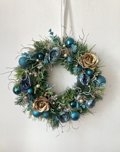 a christmas wreath hanging on the wall with blue and gold ornaments around it's edges