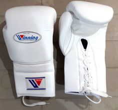 two white boxing gloves sitting on top of a tiled floor