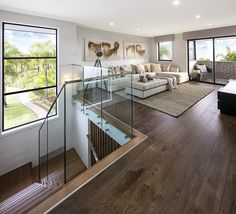 a living room filled with furniture next to a window covered in glass and wooden flooring