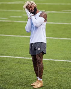 a man standing on top of a field holding his hands up to his face and covering his eyes