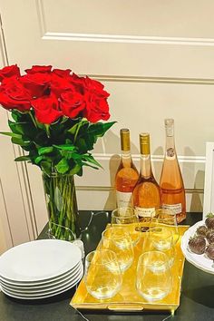 roses in vases, plates and glasses on a table with wine bottles and cookies