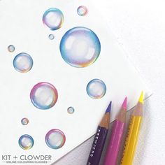 colored pencils and water bubbles on top of a piece of paper