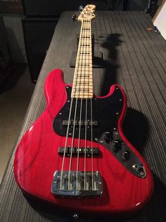 a red bass guitar sitting on top of a table