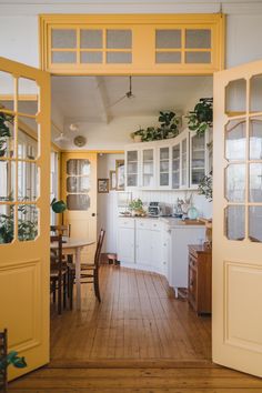 an open door leading to a kitchen with white cabinets and yellow doors on both sides