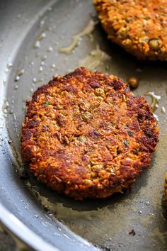 two burger patties sitting on top of a frying pan covered in oil and sprinkles