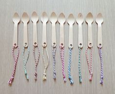 six wooden spoons are lined up with different colored striped handles and ties on them