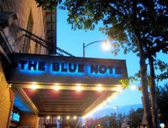 the blue note sign is lit up for people to walk in and out at night