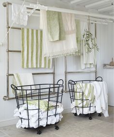 two iron beds sitting next to each other in a room with green and white towels hanging on the wall