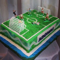 a cake with soccer players on it sitting on top of a white cloth covered table