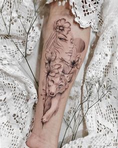 a woman's arm with flowers and a wolf tattoo on the left side of her leg