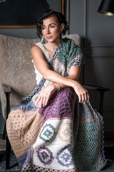 a woman sitting on a chair with a crocheted blanket