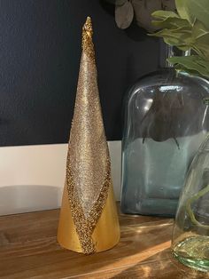 two vases with plants in them sitting on a wooden table next to each other