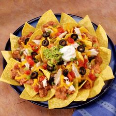 nachos with chicken, black olives and sour cream on a blue plate