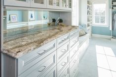 a kitchen with marble counter tops and white cabinets