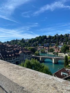 a bridge over a river with buildings on the other side and blue sky in the background