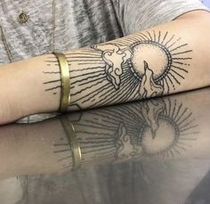 a woman's arm with a tattoo on it that has an elephant and sun in the middle