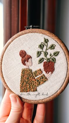 someone is holding up a small embroidery project