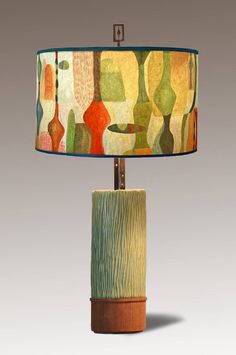 a lamp that is sitting on top of a wooden base with a green and yellow lampshade