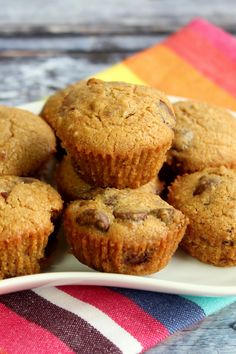 a white plate topped with muffins sitting on top of a colorful towel next to a cupcake