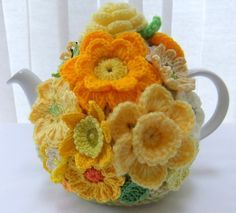 a crocheted tea pot with yellow and orange flowers