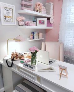 a white desk topped with a laptop computer next to a pink flower filled vase on top of it