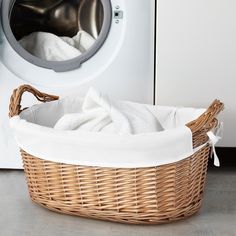 a wicker laundry basket sitting next to a washing machine with white towels in it