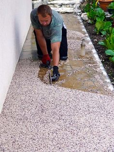 a man is working on the side of a building with his hands and feet in sand