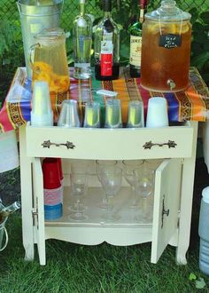 an outdoor table with bottles and glasses on it