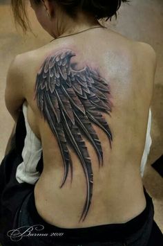 a woman's back with an angel wing tattoo on it