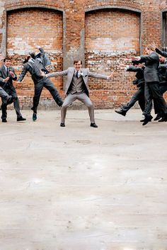 a group of men in suits and ties are dancing