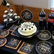 a table topped with cakes and drinks on top of a black cloth covered tablecloth