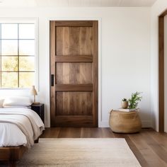 a bed sitting next to a wooden door on top of a hard wood floor in a bedroom