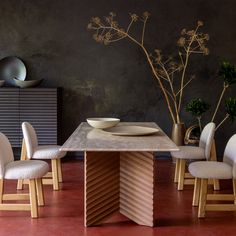 a dining room table with chairs and a bowl on the centerpiece in front of it