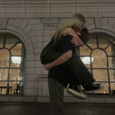 a man and woman hugging in front of a building