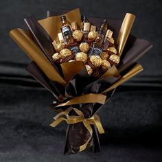 a bouquet of chocolates wrapped in gold foil and tied with a ribbon on a black surface