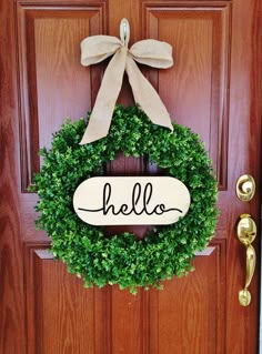 a wreath with the word hello hanging on it's front door is decorated with a bow