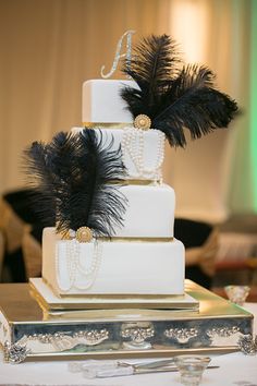 a three tiered cake with black feathers on top