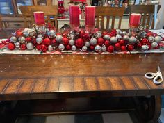 a wooden table topped with lots of red and silver christmas decorations on top of it