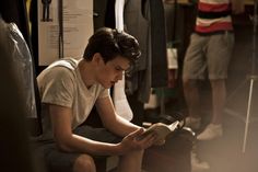 a young man reading a book while sitting on a bus