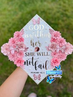 someone holding up a graduation cap with pink flowers on it that says, god is everything her she will not fail